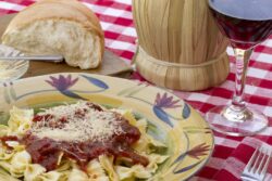 Italian pasta dinner served with Marinara sauce, Parmesan cheese, over bow tie noodles accompanied by a glass of Chianti wine and bread