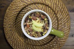 Bowl of Chicken Chili made with beans, tomatoes, onions, avocado, corn and spices