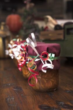 Mason jars filled with homemade orange marmalade decorated for the holidays as Christmas gifts