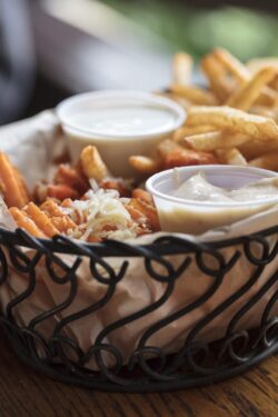 Wire basket filled with sweet potato and french fries served with aioli sauce and ranch dressing