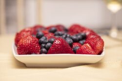Plate filled with red strawberries and blueberries on a table with linen
