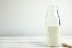 Homemade yogurt salad dressing being poured into a milk bottle