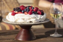 Pavlova meringue cake dessert made with strawberries, blackberries, raspberries and blueberries, planted on a granite platform