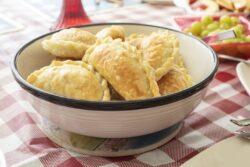 Just baked bowl of homemade Argentinian Empanadas on a table with other food for a celebration