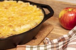Shephers Pie baked in a cast iron skillet and placed on a wood tray with an apple and napkins