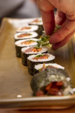 The process of making sushi and slicing during a chef's demonstration class in a home kitchen and being placed on a plate