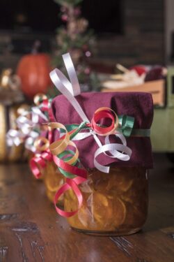 Mason jars filled with homemade orange marmalade decorated for the holidays as Christmas gifts