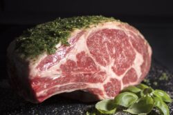 Raw prime ribeye roast prepared with a parley and salt rub ready to be roasted in the oven