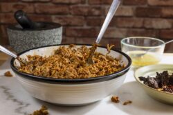 Cooking and processing pulled pork with a red ancho chili paste and pork stock, on a white marble cutting board top