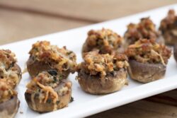 Sausage and Cheese baked stuffed mushrooms plated on white ceramic on a wood table