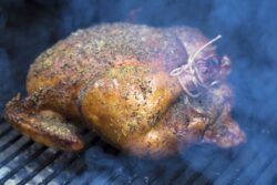 Spiced rubbed chicken being grilled in a smoker barbeque