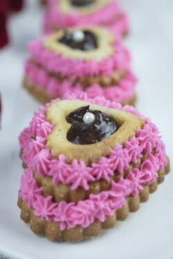 Heart shaped cupcake with pink icing and ganache filling, garnished with red roses.