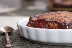 Golden raisin andbaked bread pudding cake served on a plate on a table.