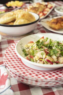 Ceviche plated in a bowl, surrounded by a variety of foods for a party celebration on a holiday
