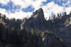 Granite formations shaped like a bear with pine trees surrounding and blue sky in Yosemite Valley, California