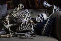 Halloween skeleton family with mom and kids playing on a couch for the holiday season