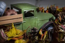 Toy harvest truck and pumpkins home decor surrounded by fall garlland for Halloween or Thanksgiving decorations