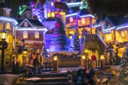 Miniature Christmas village scene with houses, trees, people, dogs and cats celebrating the holidays