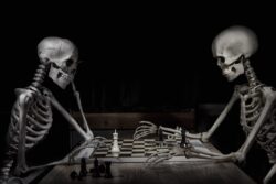 Chess game set up by two Halloween skeletons on a wood table
