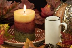 A cup of coffee with a lit candle and pumpkin decoration as a fall table setting