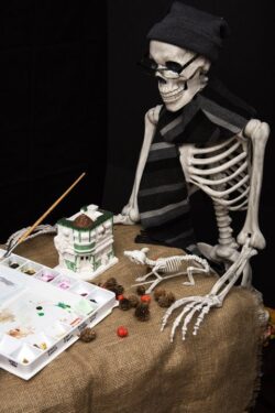 Halloween skeleton holding a brush and painting statuary and decorations for the celebration