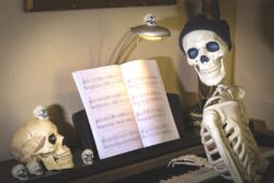 Halloween skeleton and skulls at a piano decorated for the holiday